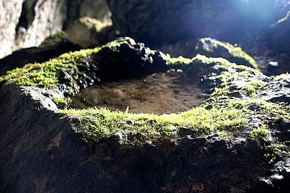 A természetes kőmélyedésbe kristálytiszta víz csepeg a barlang mennyezetéről.