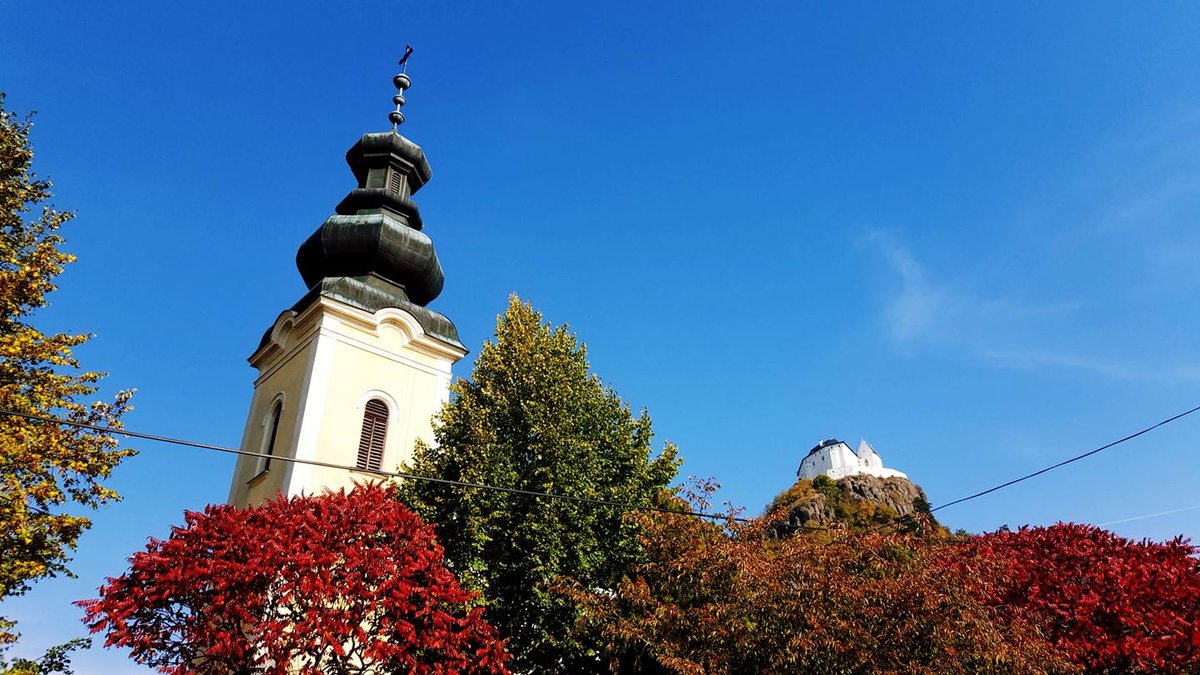 A Szent István Római katolikus templom tornya és a Füzéri vár a háttérben